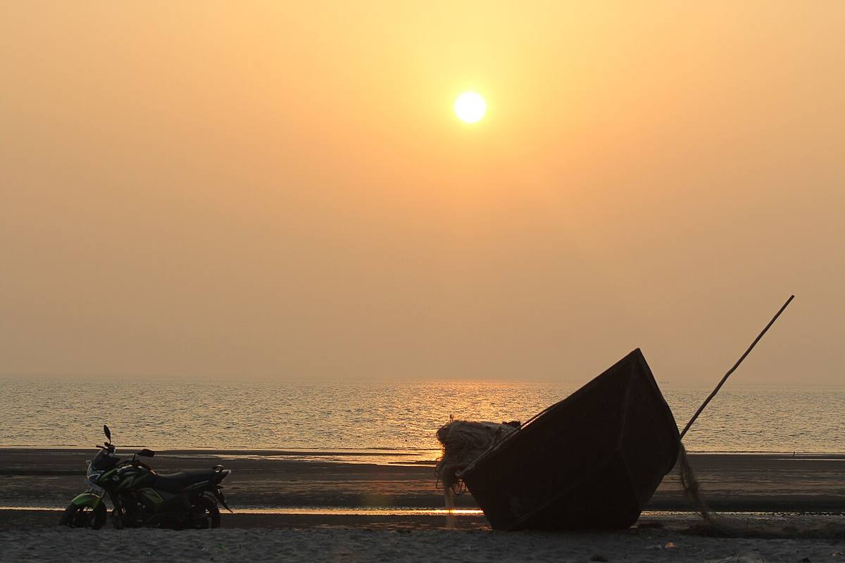 A fishing boat silhouetted at sunset on Kuakata beach