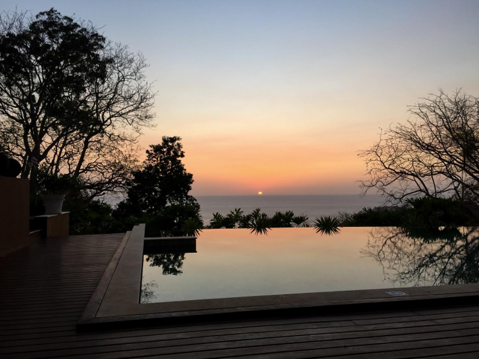 An infinity pool at dusk overlooking the water